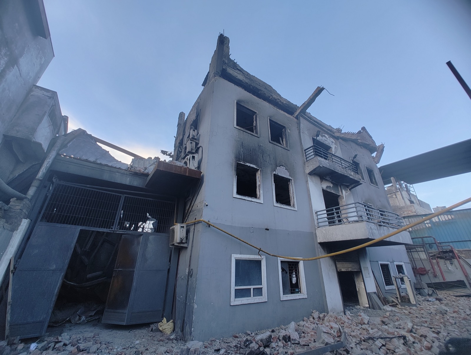 A three-storey building with burnt windows and a collapsed roof after a fire