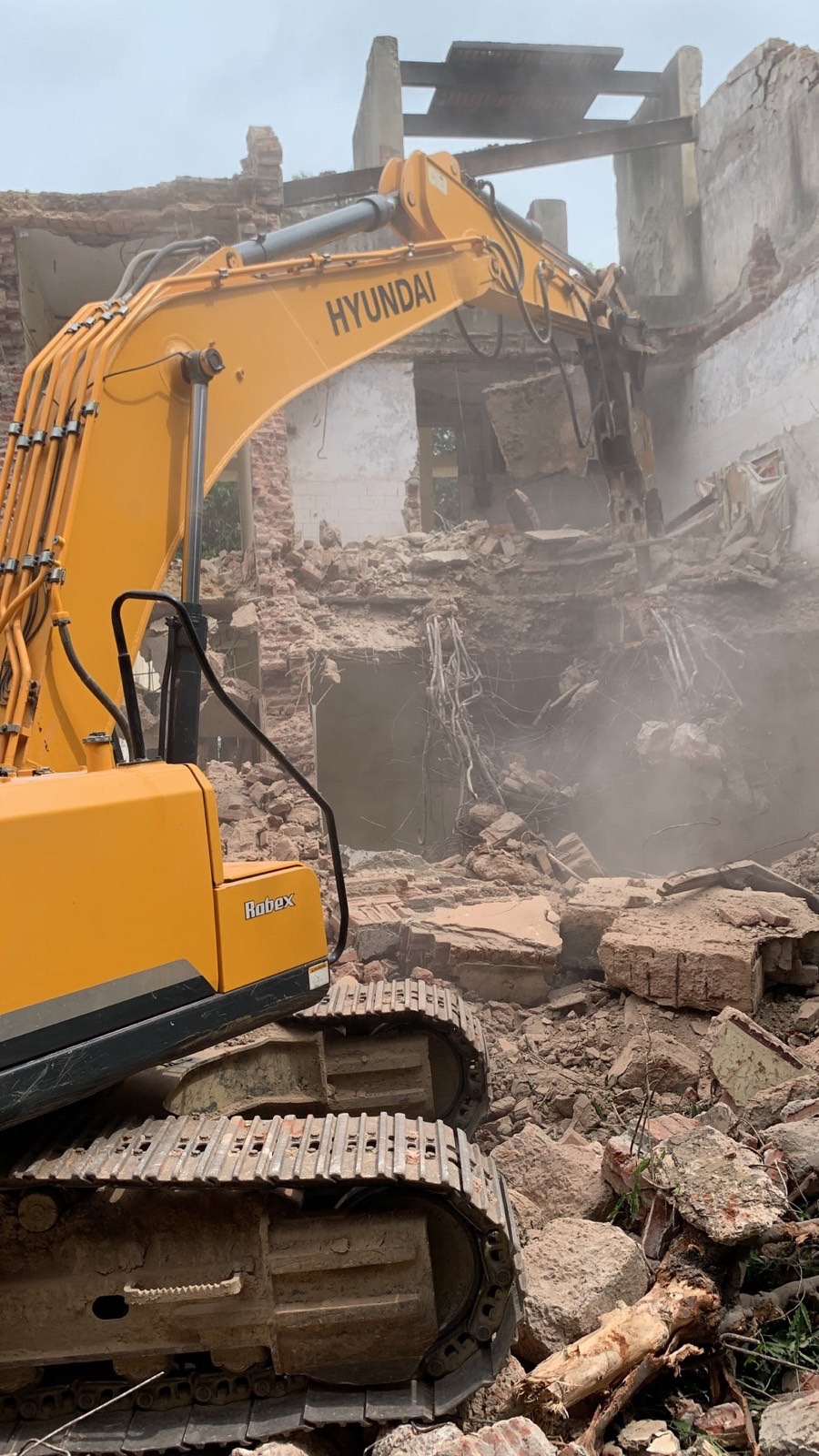 Excavator arm inside a partly demolished house, pulling masonry down